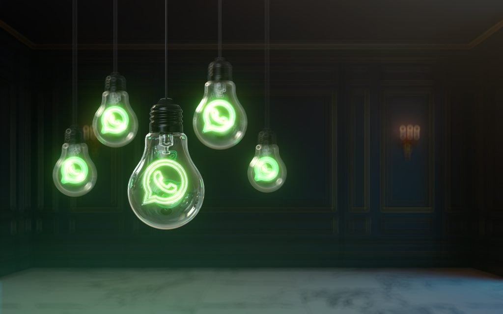 Lâmpadas incandescentes penduradas com o logotipo do WhatsApp iluminado enfatizam a inovação e comunicação brilhante do aplicativo.