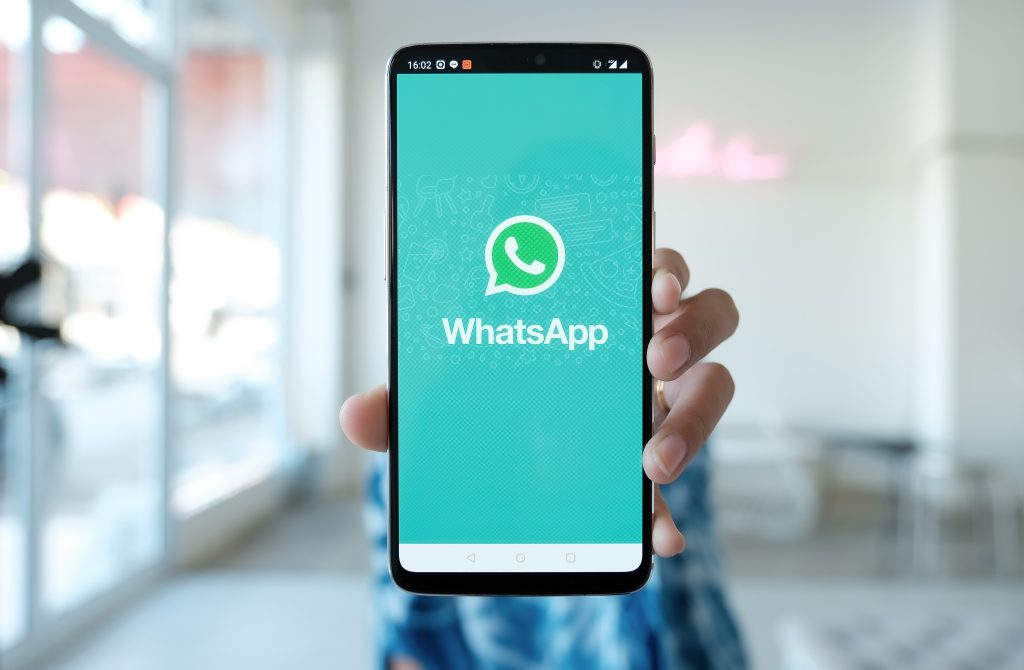 Smartphone em mãos mostrando a tela inicial do WhatsApp, simbolizando sua centralidade na vida digital cotidiana dos usuários.