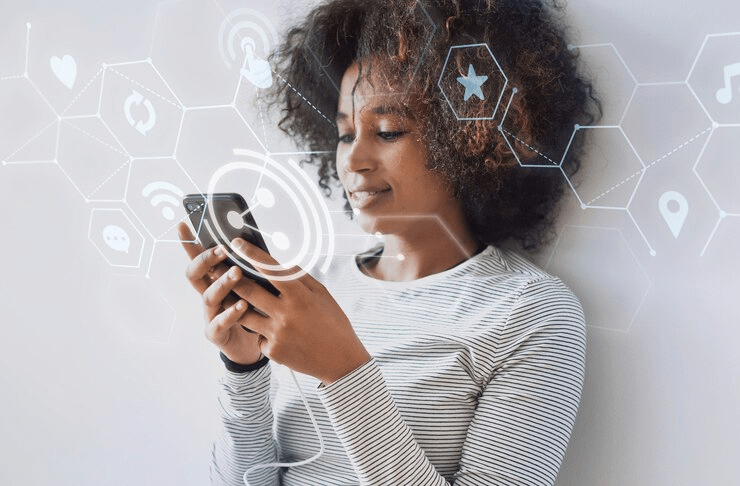 Jovem utilizando smartphone com ícones de mídia social flutuantes destaca a conectividade omnichannel no cotidiano digital.

