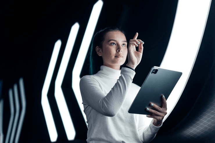 Mulher jovem e moderna usando tablet com gráficos interativos ao fundo demonstra a navegação intuitiva na era omnichannel.

