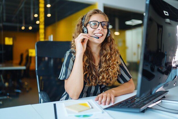  Uma atendente sorridente com headset em um ambiente de escritório, representando a substituição de sistemas de telefonia tradicionais por soluções de VoIP mais econômicas.