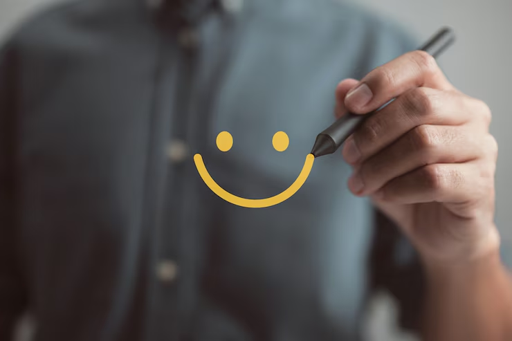 Mão desenhando um smiley face com um marcador, uma metáfora visual para a satisfação do cliente, um objetivo chave em operações de call center.
