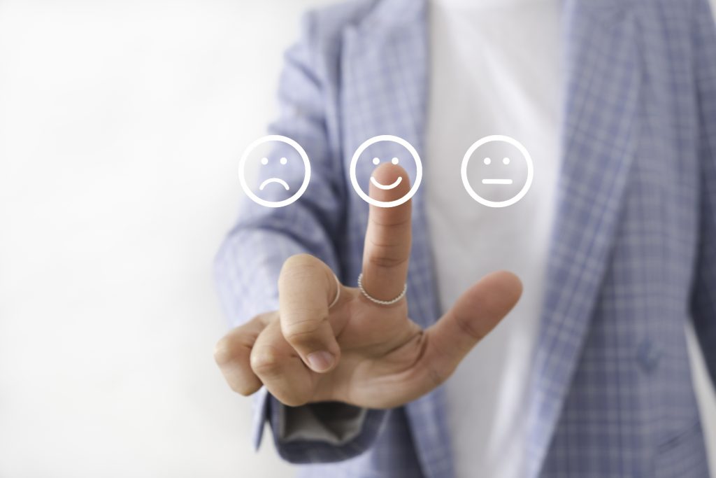 Um empresário está selecionando um rosto sorridente em uma interface touchscreen, indicando a satisfação do cliente ou seleção de feedback.