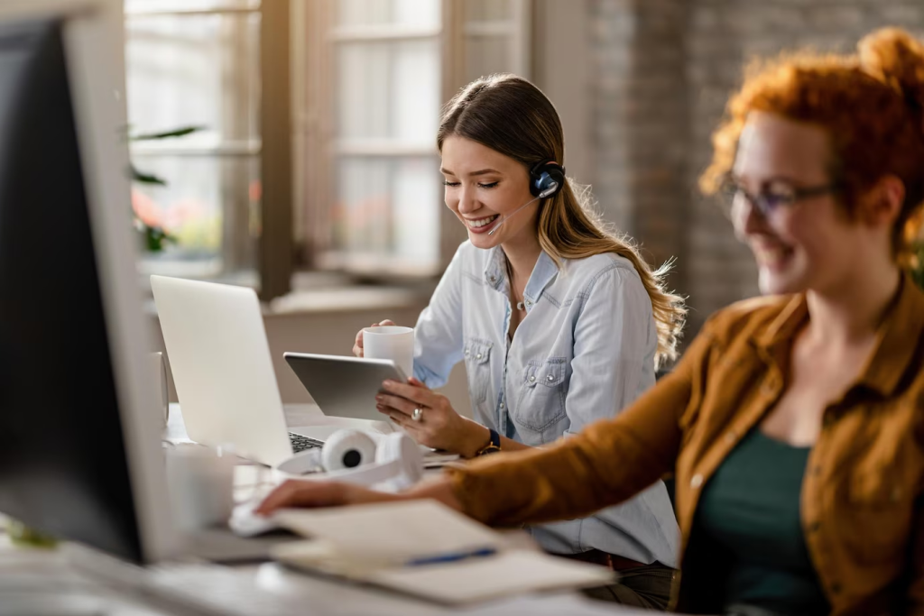Atendente sorridente com headset navegando em um tablet exemplifica a excelência no atendimento ao cliente multitarefa no ambiente de trabalho.
