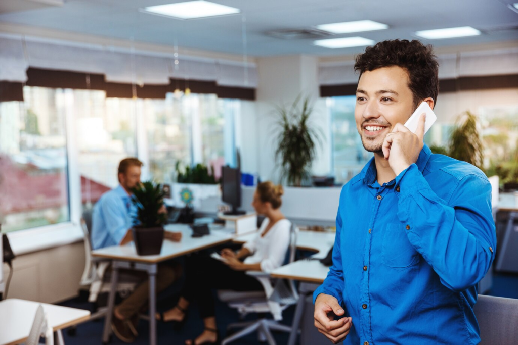 Um atendente de serviço 0800 sorridente conversa com um cliente por telefone, refletindo a eficiência e a proximidade que pequenas e médias empresas podem oferecer.