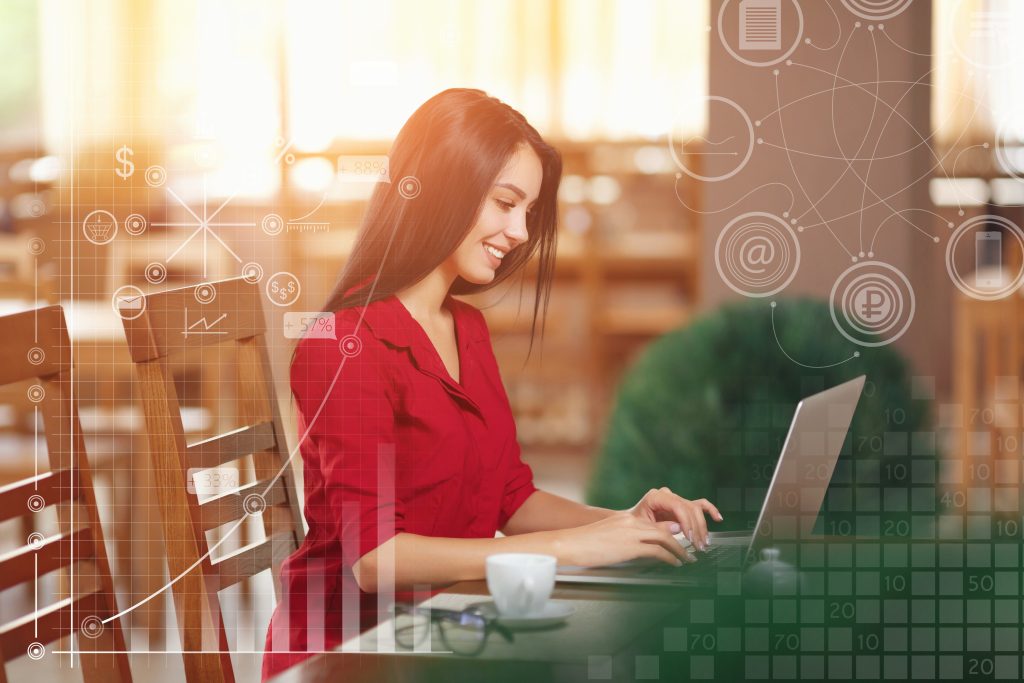 Profissional feminina trabalhando em um laptop em um café, com gráficos virtuais de software envolvendo a cena, indicando uma conexão com softwares de comunicação e finanças. 