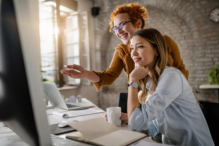 Duas profissionais colaborando no escritório, utilizando um computador para planejamento estratégico. A imagem exemplifica a cooperação no ambiente de trabalho moderno, destacando o uso eficaz de tecnologia para soluções empresariais.





