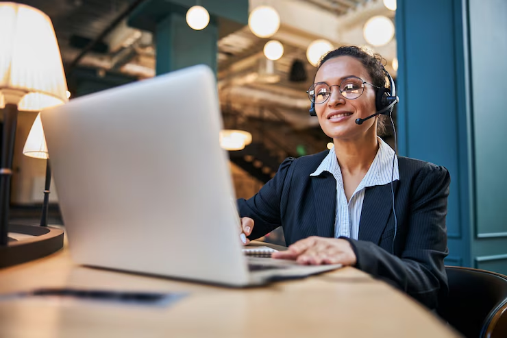 Consultora de atendimento ao cliente trabalhando em um ambiente moderno de coworking, usando fone de ouvido e laptop para auxiliar clientes, refletindo um serviço profissional e eficiente.