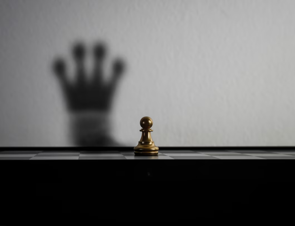 Peão de xadrez em um tabuleiro com a sombra de uma coroa projetada na parede, simbolizando estratégia e transformação em negócios, elementos cruciais para entender 'O que é SaaS?' no contexto de liderança no mercado.