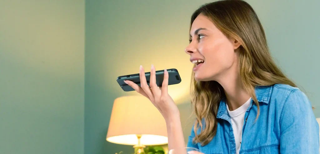 Mulher segurando o celular e enviando mensagem por voz, representando o uso estratégico do disparo de voz para alcançar o público de forma efetiva.