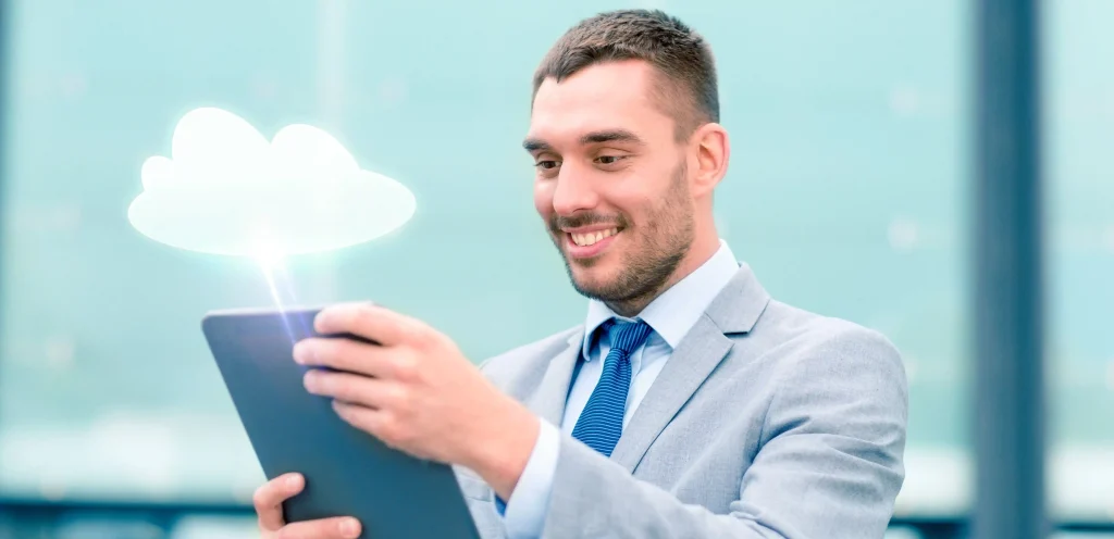 Homem de terno usando tablet com ícone de nuvem flutuando, representando o uso de sistema de atendimento em nuvem para empresas.