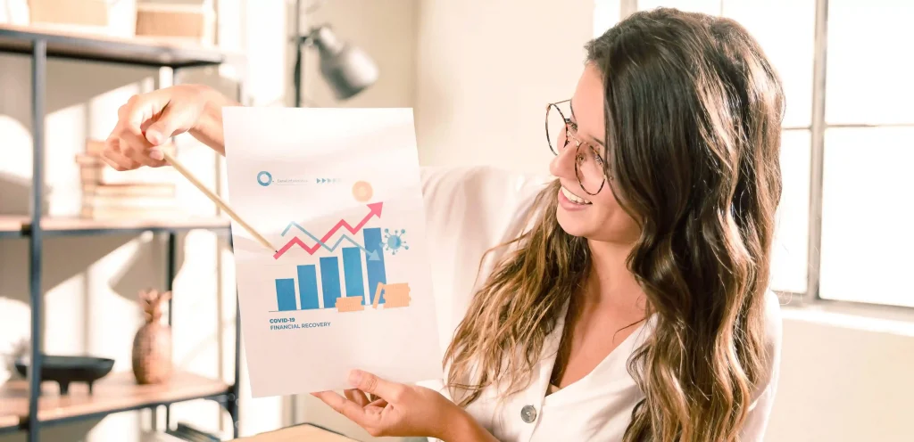 Mulher sorridente aponta para gráfico com barras e linhas de crescimento, ilustrando o conceito de funil de vendas e resultados positivos.