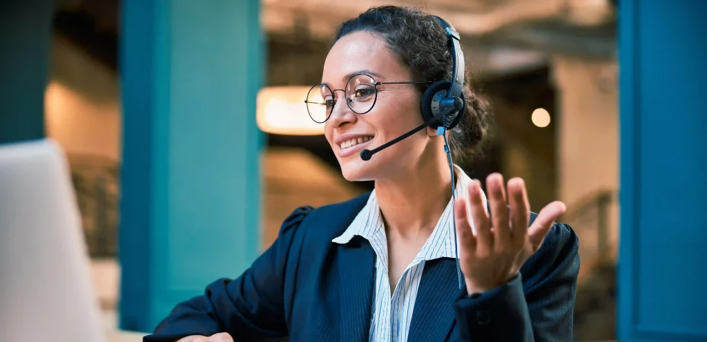 Mulher com headset sorrindo durante atendimento online, ilustrando os benefícios de contratar um serviço de 0800 para atendimento ao cliente.
