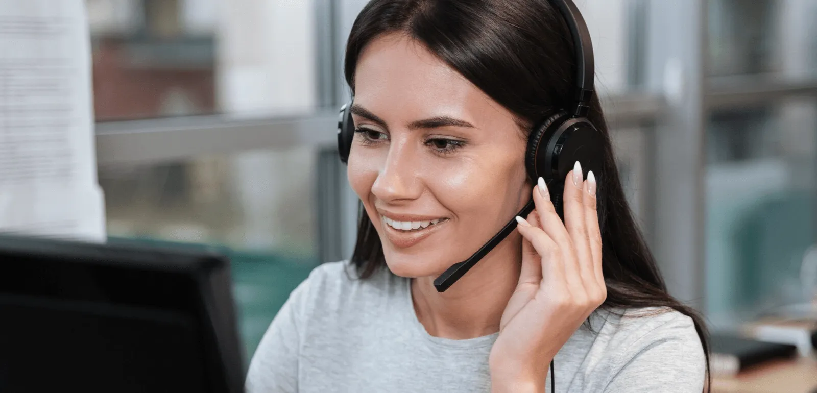 Profissional de atendimento ao cliente usando headset e computador durante uma das etapas do atendimento personalizado