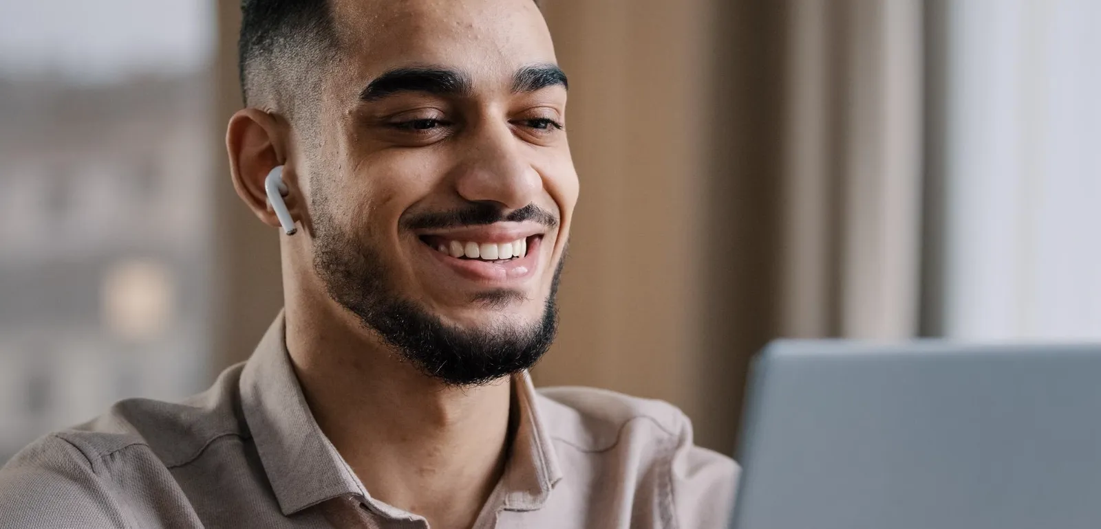 Homem sorridente usando fone de ouvido e notebook