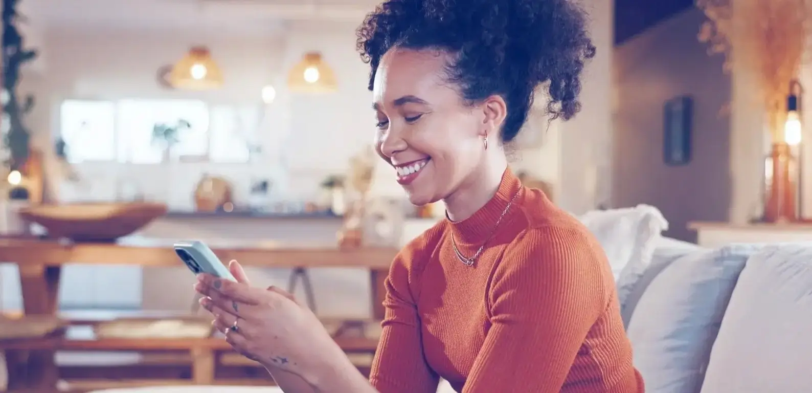 Mulher sorrindo enquanto acessa o SAC pelo celular, representando um atendimento ao cliente moderno e eficiente