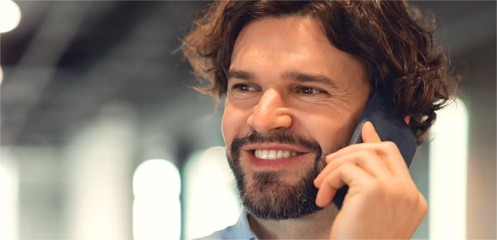homem sorridente falando ao telefone em ambiente corporativo