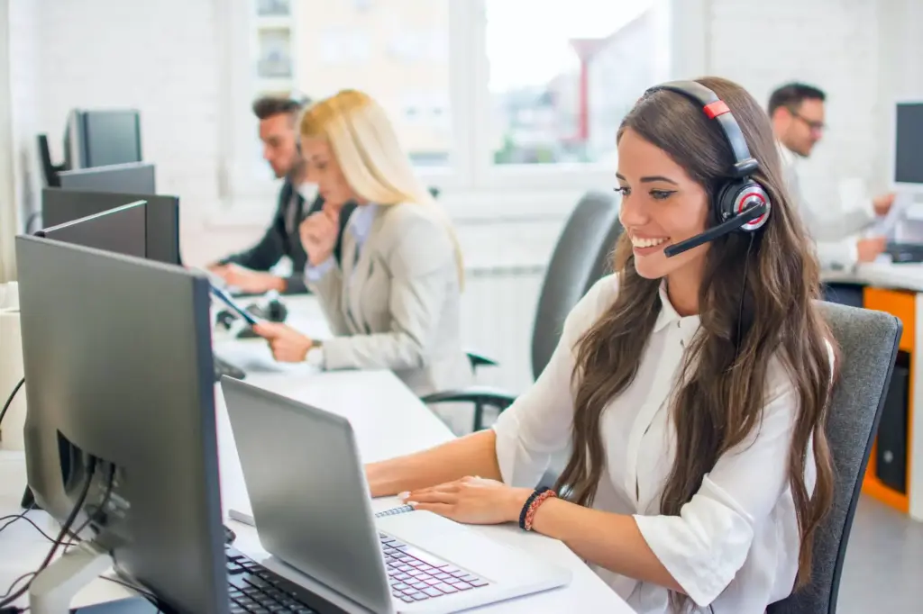 Equipe de atendimento usando VoIP em call center com headsets e computadores