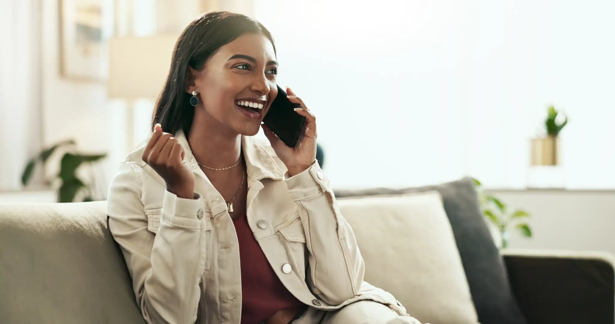 Mulher sorridente atendendo ligação pelo celular com suporte do PABX na nuvem em casa