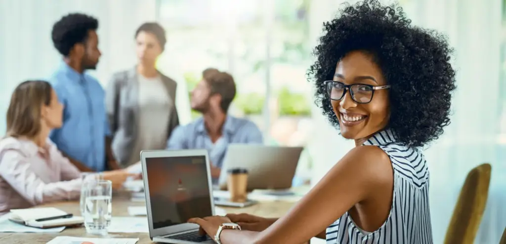 Profissional sorrindo em reunião de negócios com laptop e plataformas whatsapp