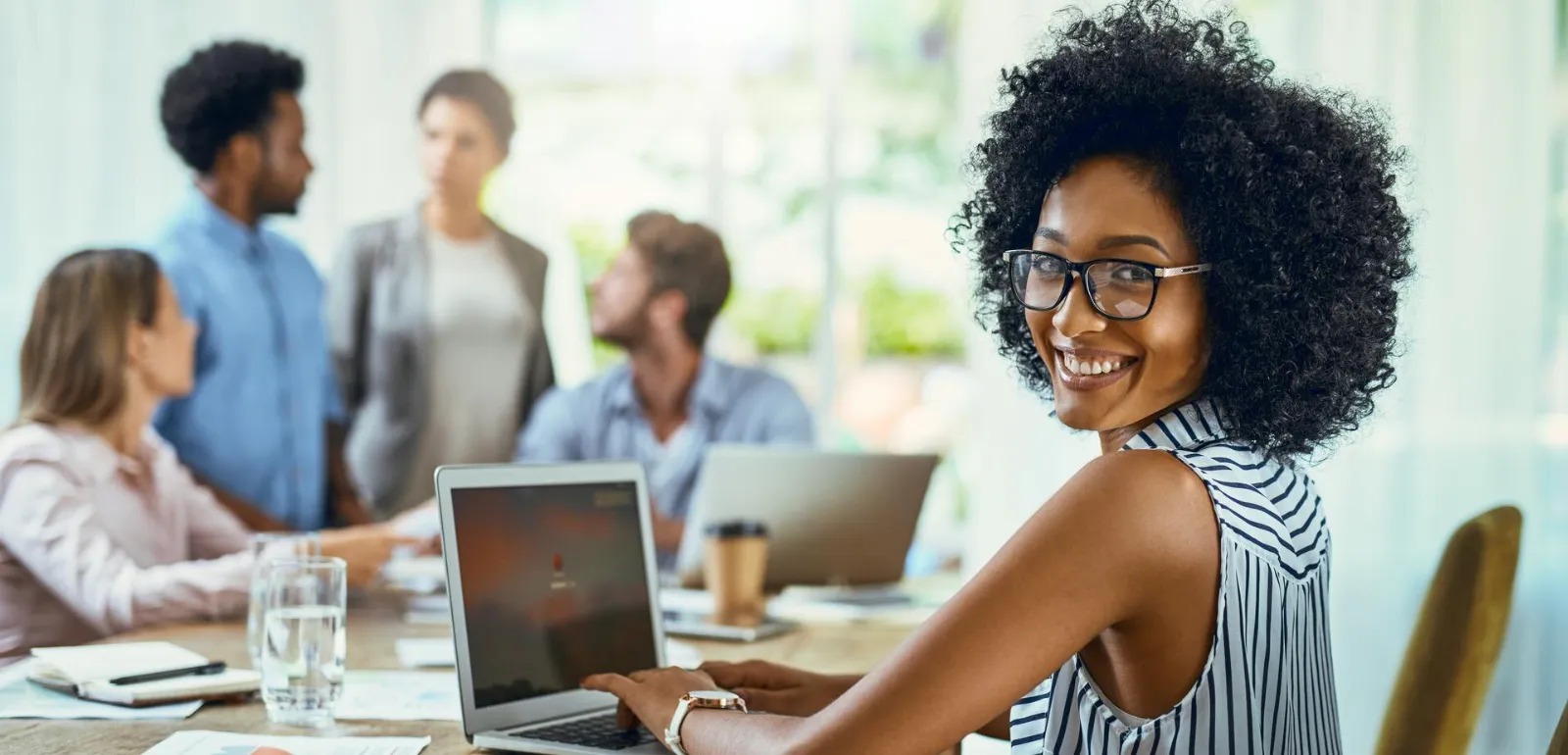 Profissional sorrindo em reunião de negócios com laptop e plataformas whatsapp